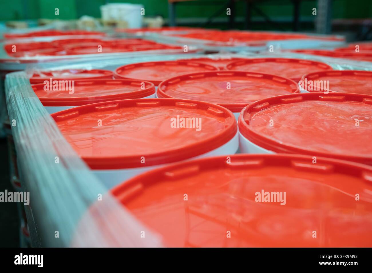 Close-up of paint containers with red covers wrapped together into stretch film at warehouse Stock Photo
