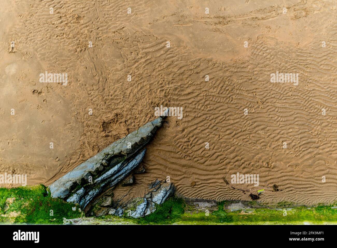 Fine sandy beach texture and stone partly visible. Stock Photo