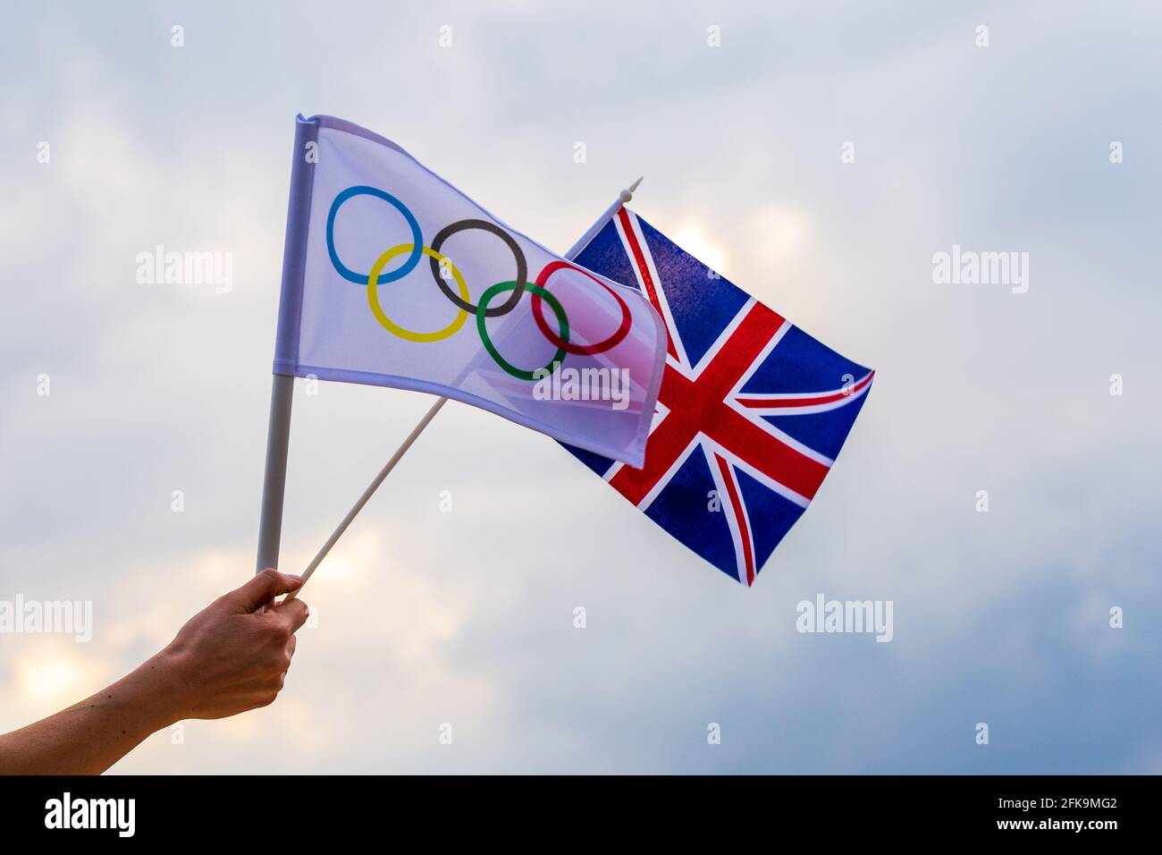 Fan waving the national flag of  United Kingdom and the Olympic flag with symbol olympics rings. Stock Photo