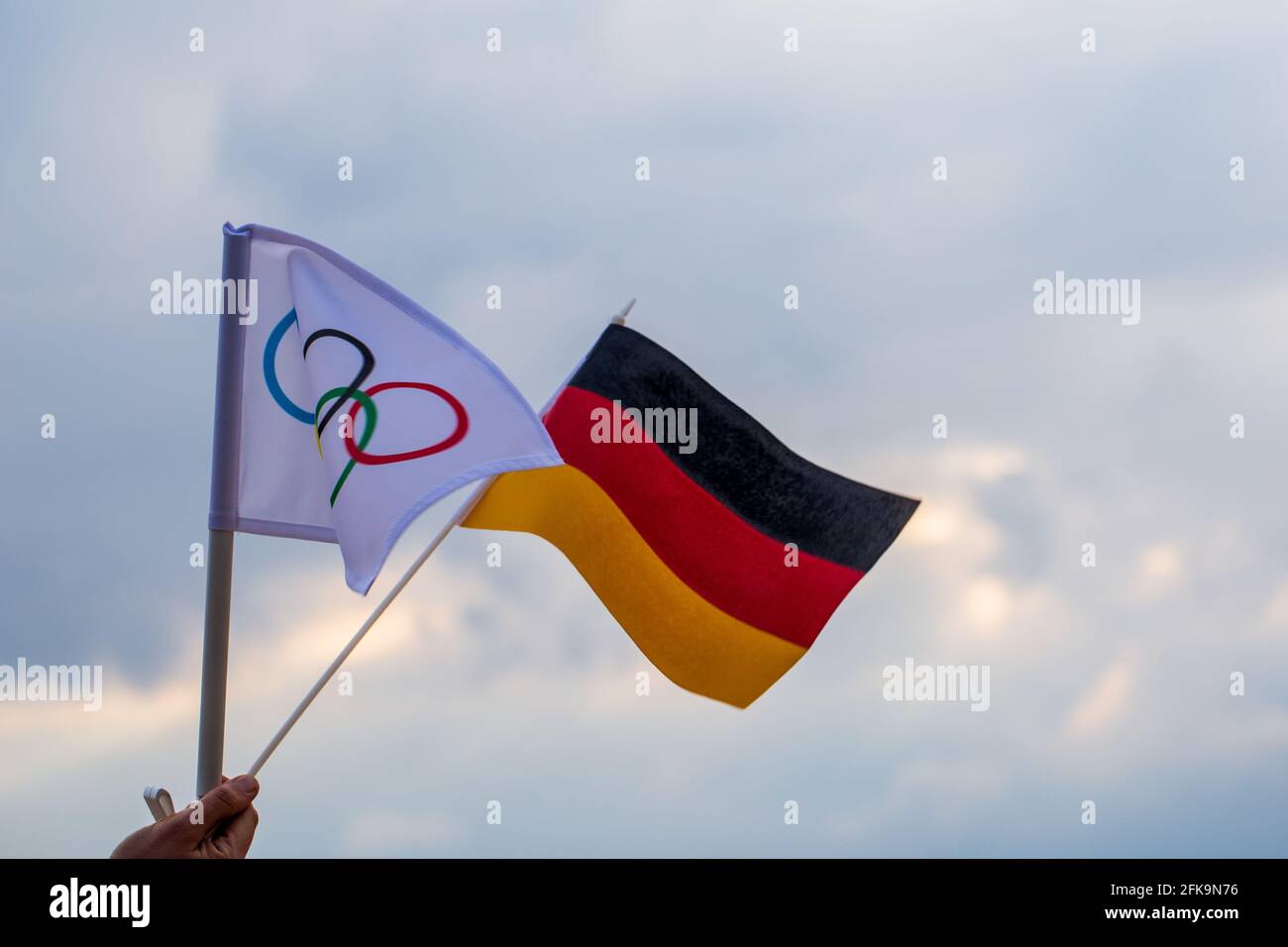 Fan waving the national flag of  Germany and the Olympic flag with symbol olympics rings. Stock Photo