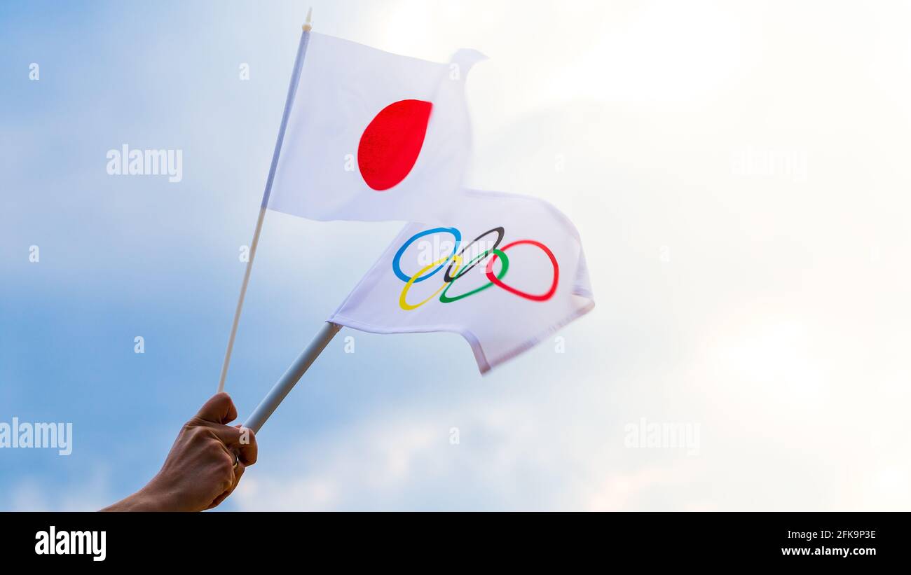 Fan waving the national flag of Japan and the Olympic flag with symbol olympics rings. Stock Photo