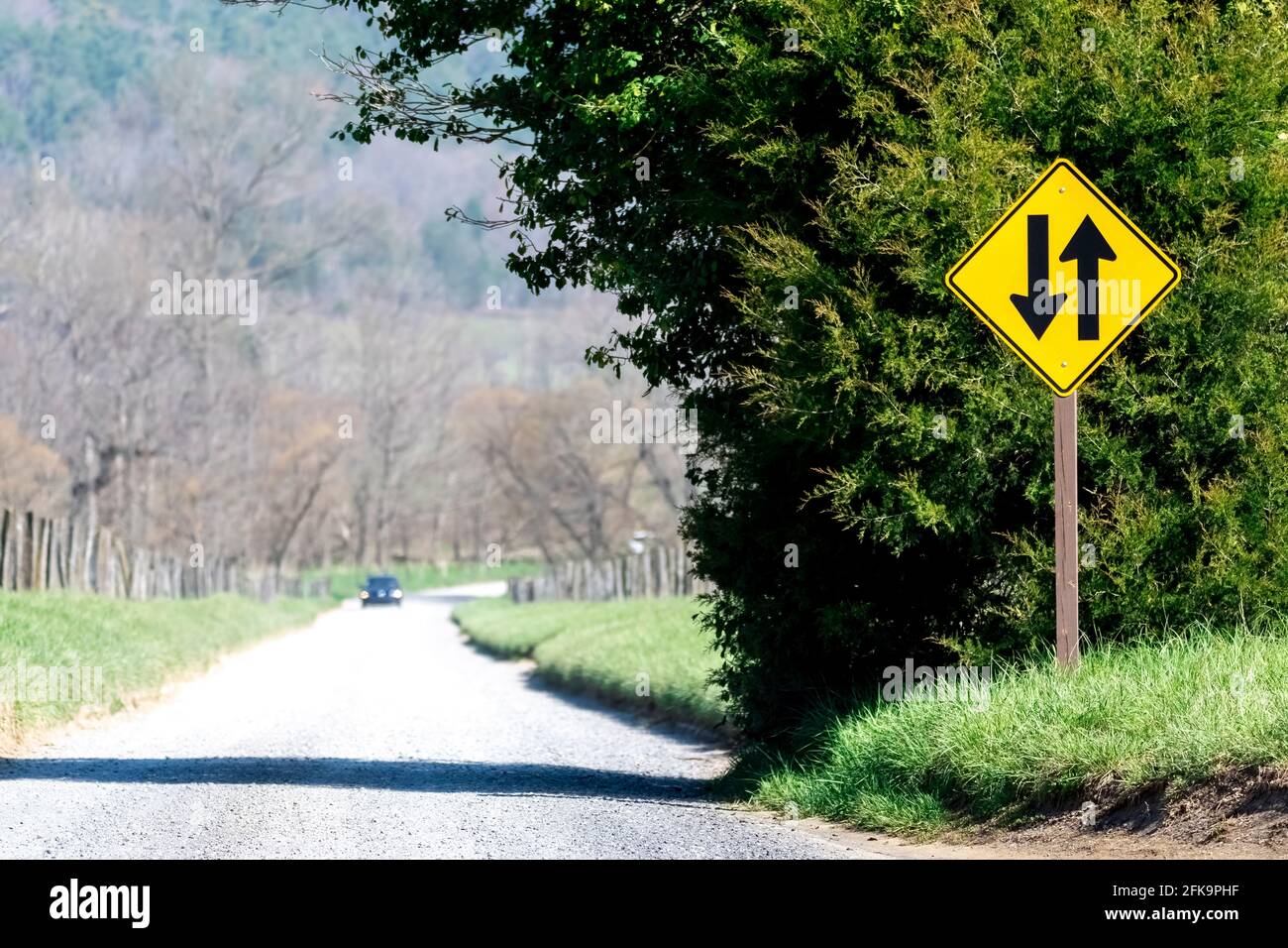A lonely country road with a distant car approaching. Stock Photo