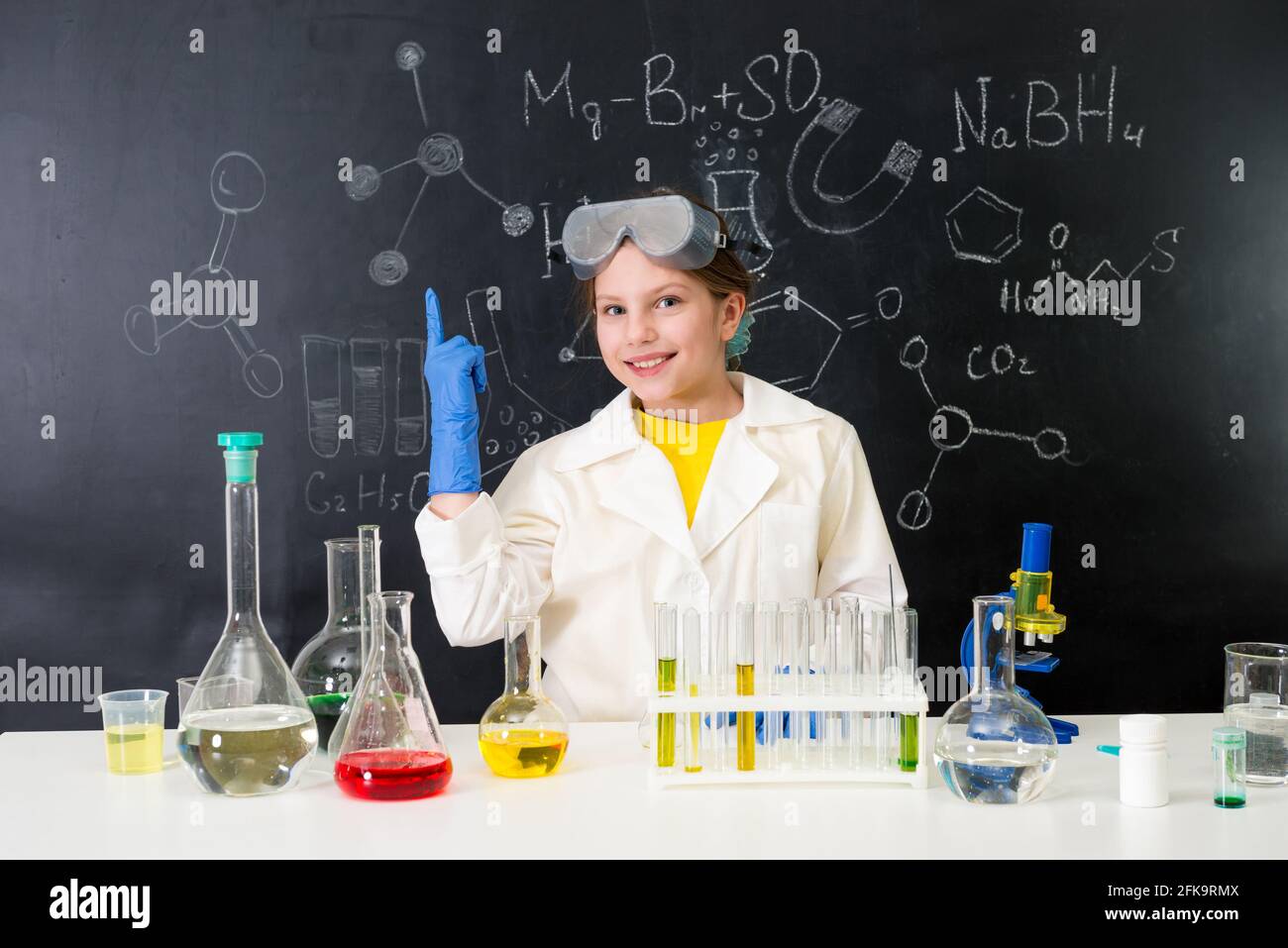 schoolgirl in chemistry lab pointing at formula on blackboard Stock ...