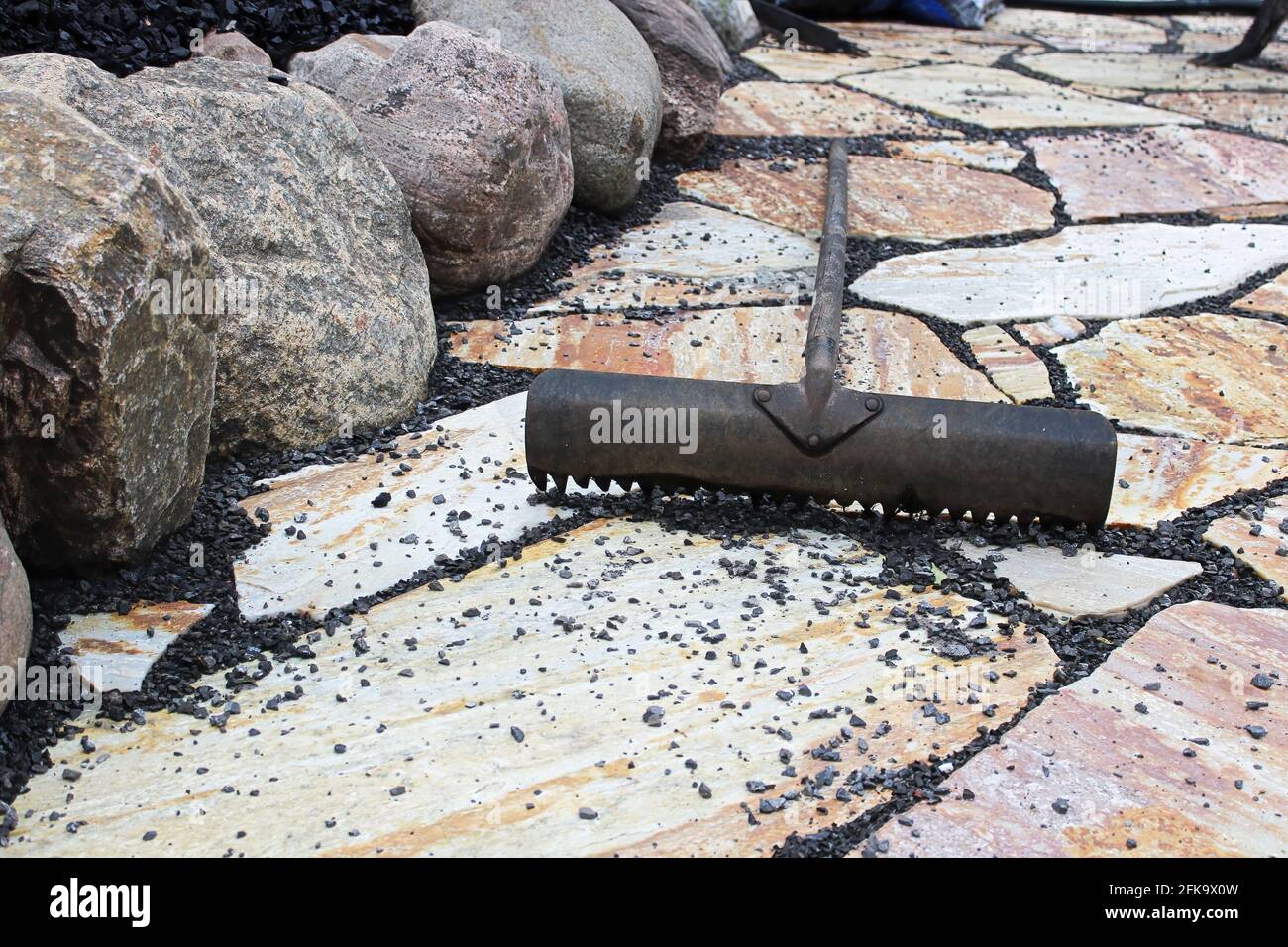 Pedrick Stone Rack A rack being used to place black pebbles between patio stones Stock ...