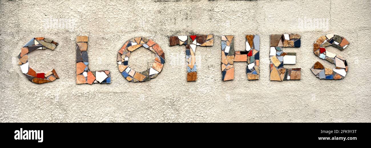 The word clothes is formed from broken tile pieces.  Letters are mounted on concrete wall. Stock Photo