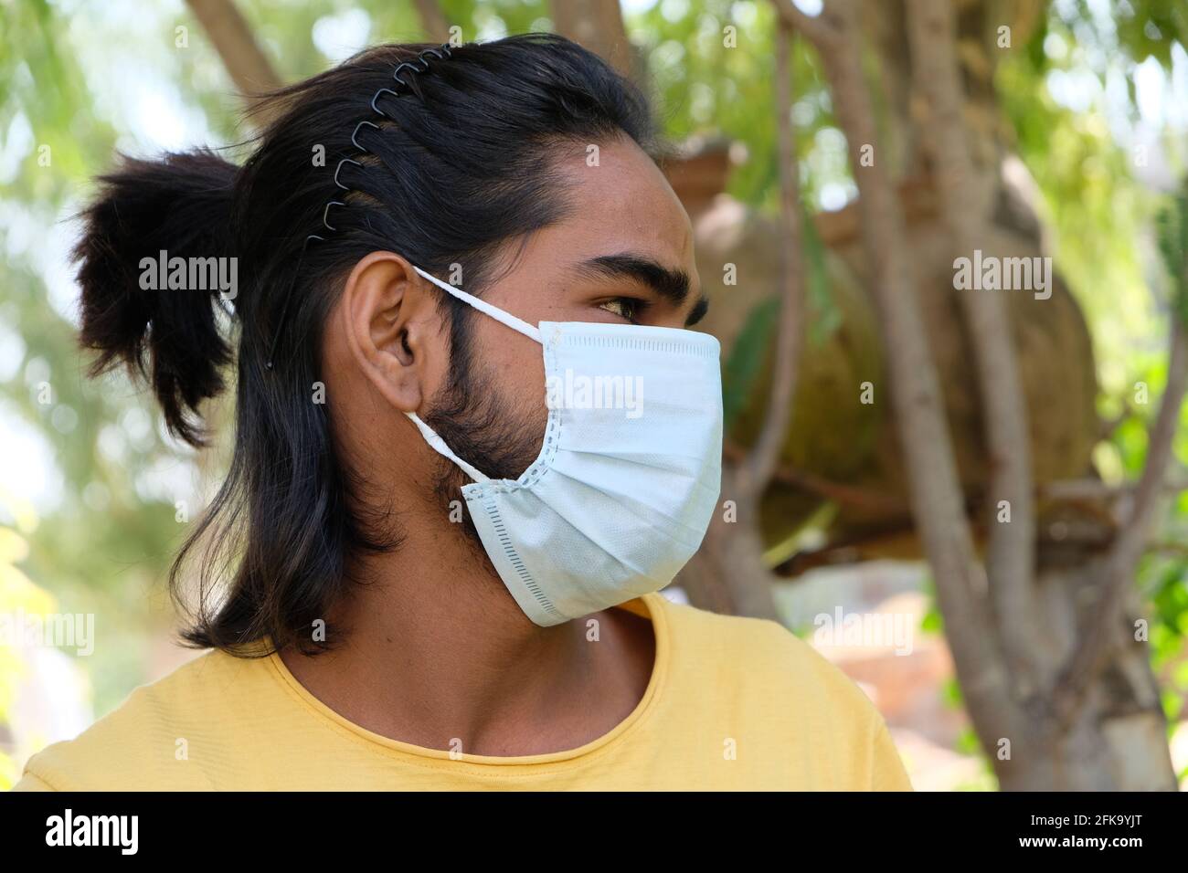 Profile portrait of a young Indian male with long hair wearing a medical  mask in a park Stock Photo - Alamy