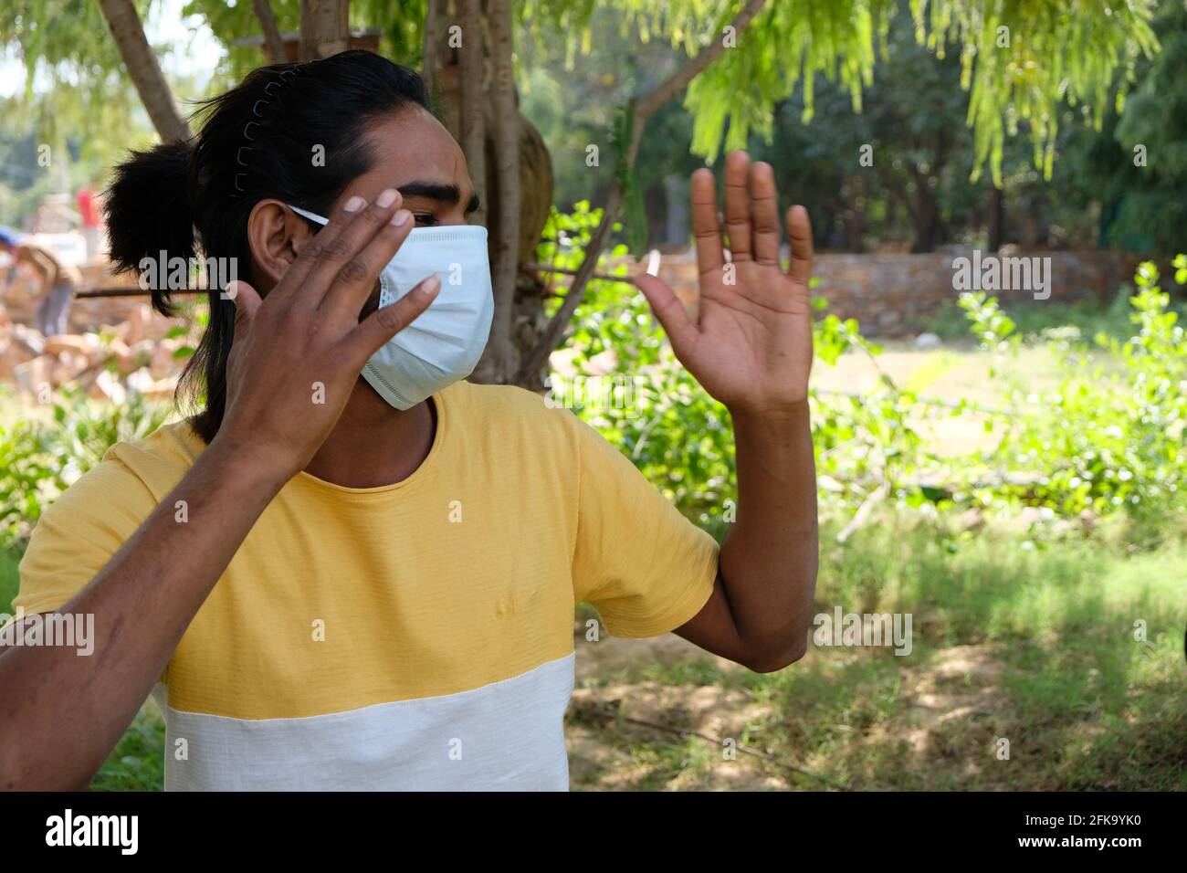 Young Indian male with long hair wearing a medical mask in a park ...