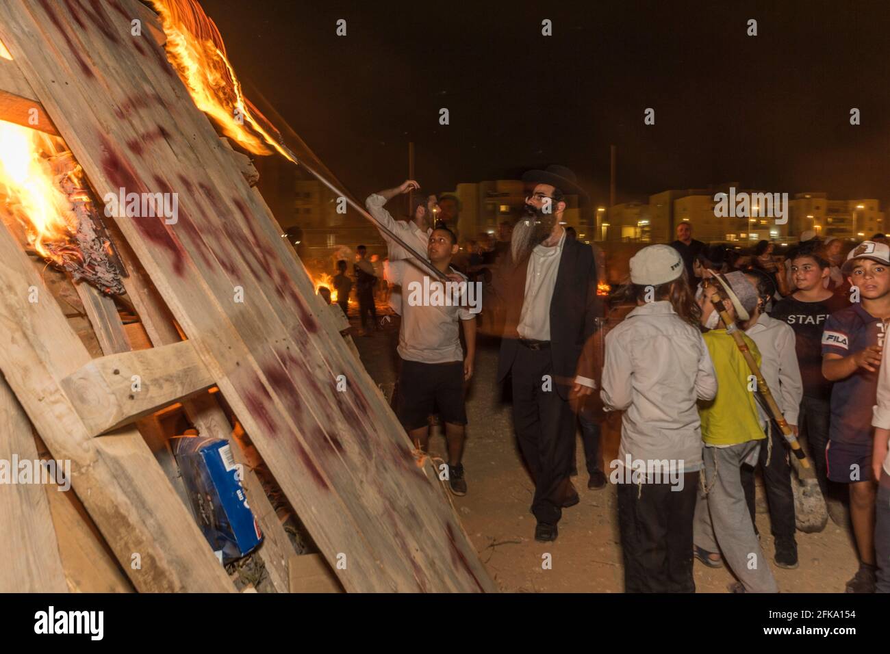 A Rabbi lights a large pyre during the Jewish Holiday of Lag Ba'Omer, which takes place every  18th of Hebrew month Iyar. It is customary during this holiday to make fires. This year, due to fire hazard warning, all fires were concentrated to few sites, hence the large number of pyres. Stock Photo