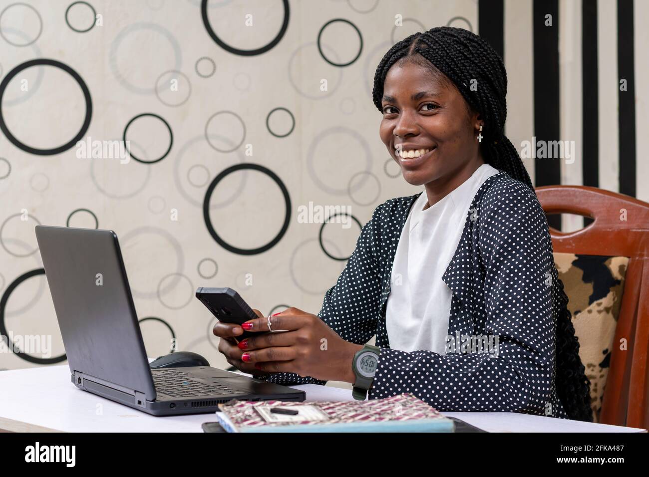 African businesswoman smiling while operating her phone in the office ...