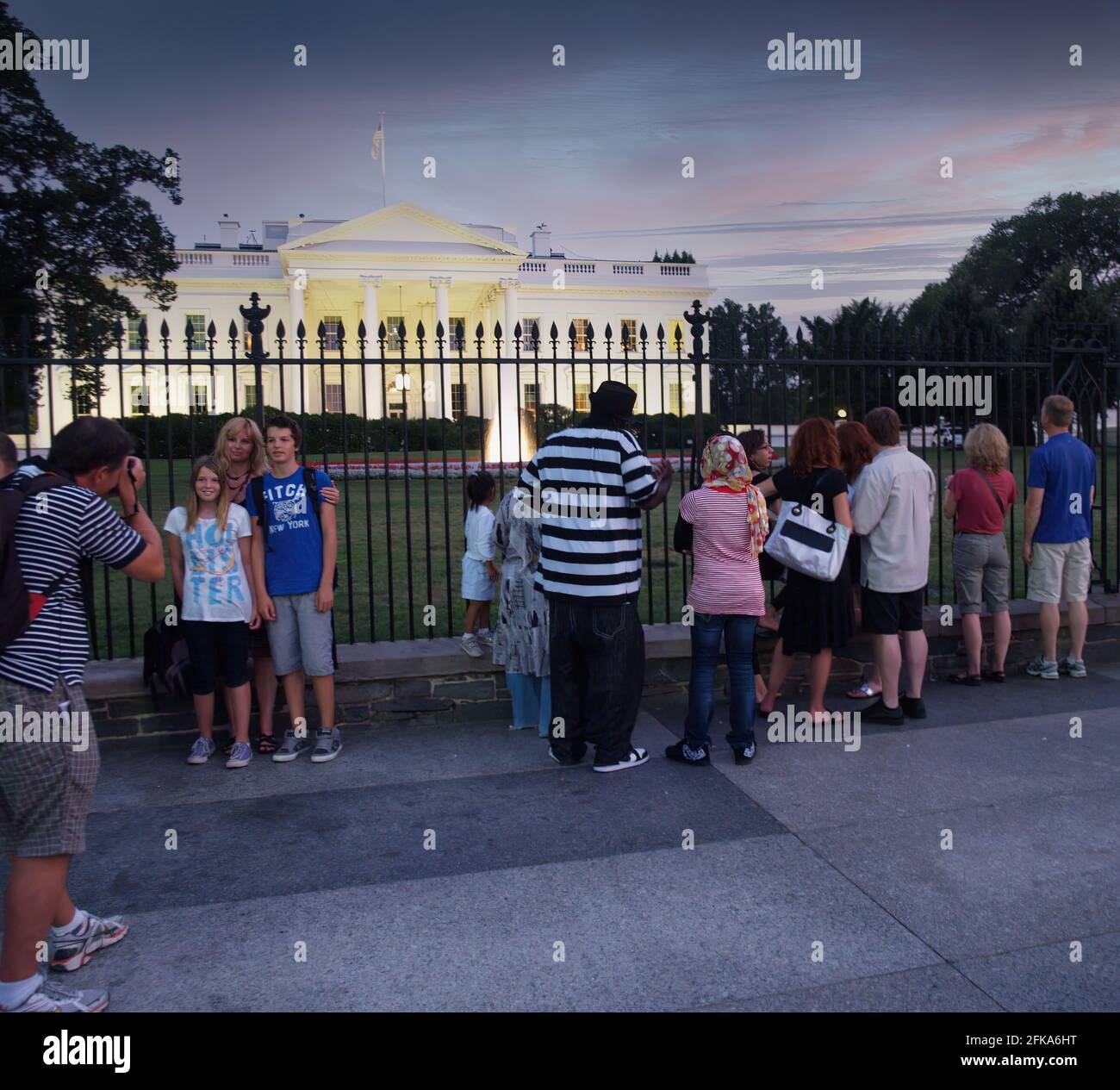 Tourists gaze through the iron fence and take photos of the White House in August 2010 during the Obama administration. Stock Photo