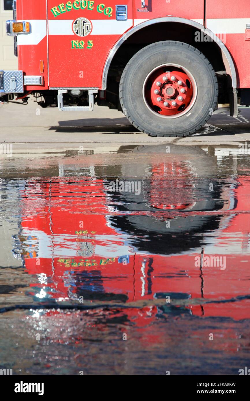 Reflection of red fire engine in water on street Stock Photo
