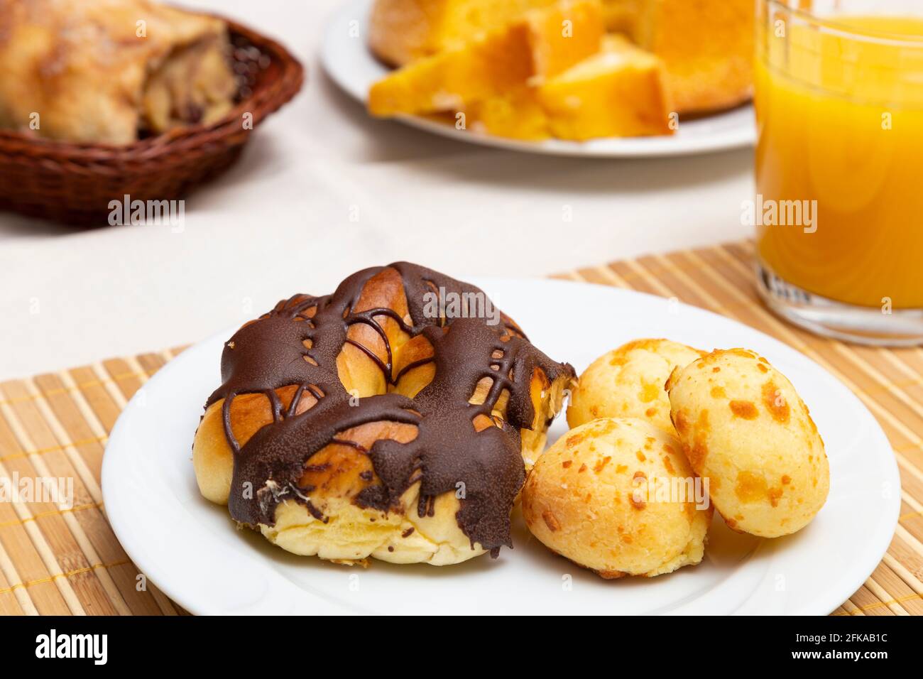Close up of plate with thread with chocolate icing and cheese bread. Orange juice. Stock Photo