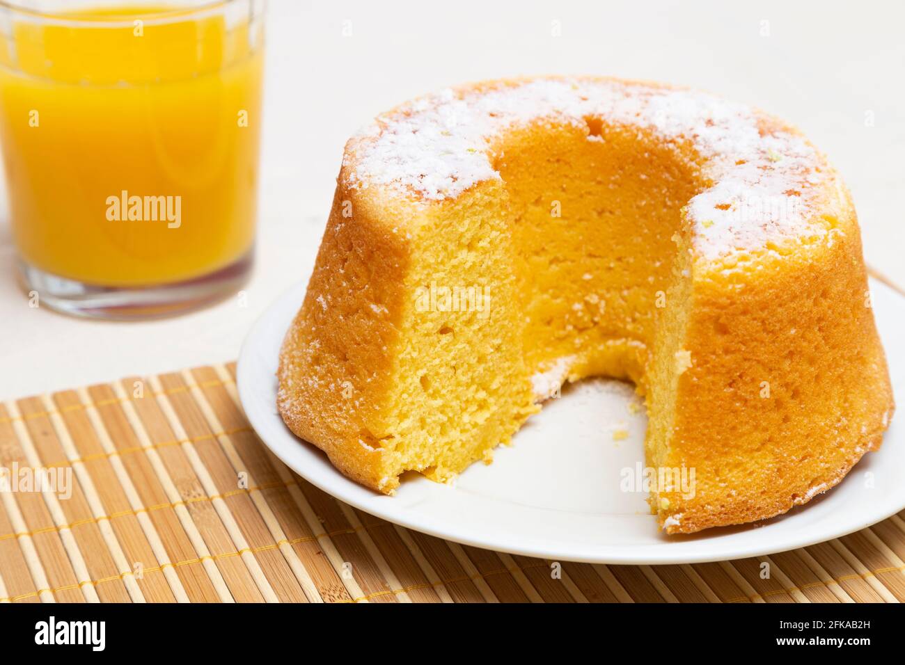 Orange cake with a little icing sugar and a glass of orange juice. Stock Photo