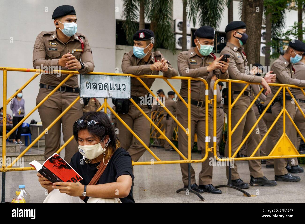 Bangkok, Thailand. 29th Apr, 2021. A protestor reading the 1984, a dystopia novel written by George Orwell, in front of a police barricade following the denial of bail requests of all 7 detained protestors, including Penguin who is on his 45th day of hunger strike. Parit 'Penguin' Chiwarak's condition worsens and other 6 pro-democracy leaders as they remain in custody for lesse-majeste law aka article 112 at the Criminal Court that saw no reason to change its previous orders. Credit: SOPA Images Limited/Alamy Live News Stock Photo