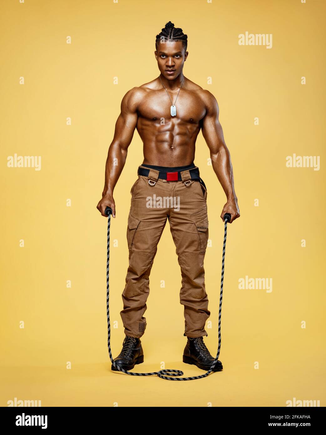 Tired man with a skipping rope. Photo of sporty muscular man with perfect body on yellow background. Best cardio workout. Stock Photo