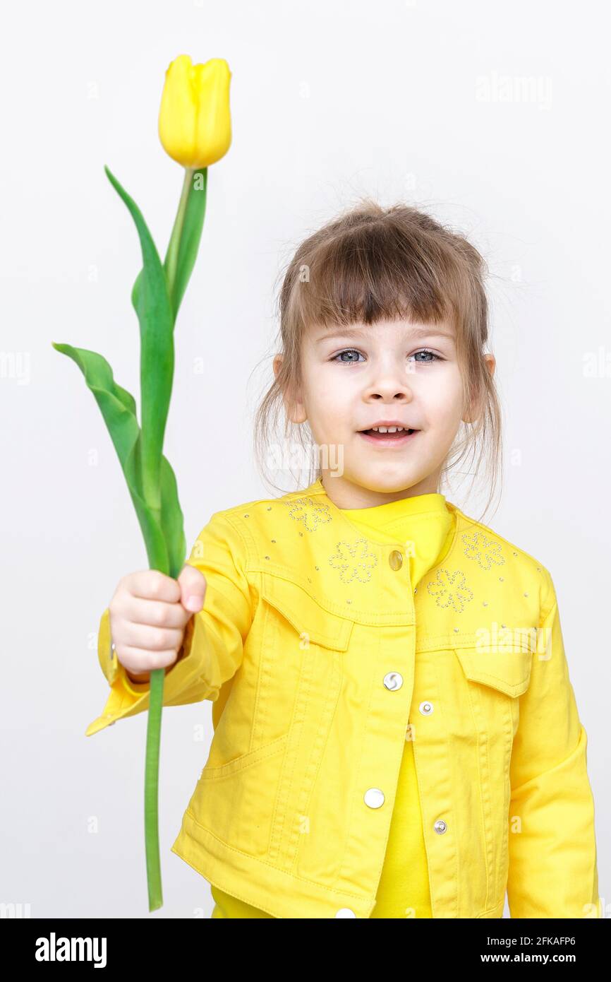 cute baby girl in yellow clothes with yellow flowers on gray background ...