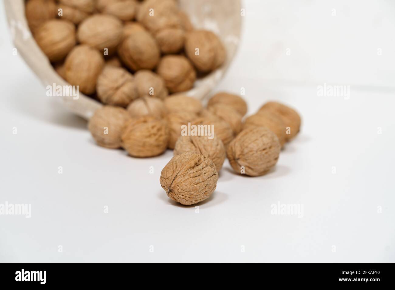 Walnuts in a wicker basket on a white background. Stock Photo