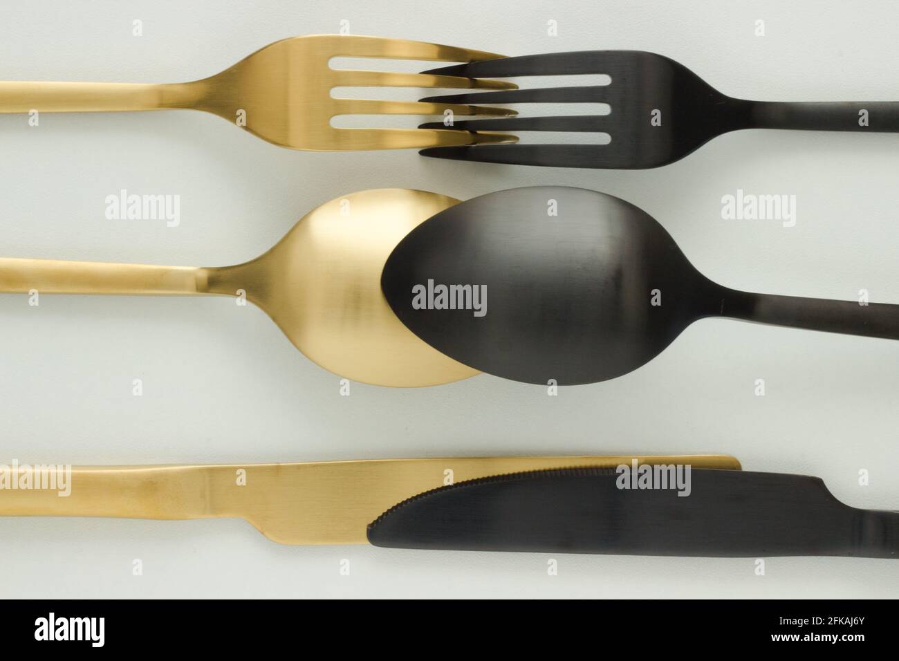 Golden and black fork, knife and spoon on white background; cutlery; cut out; creative flat lay; Art Deco Stock Photo