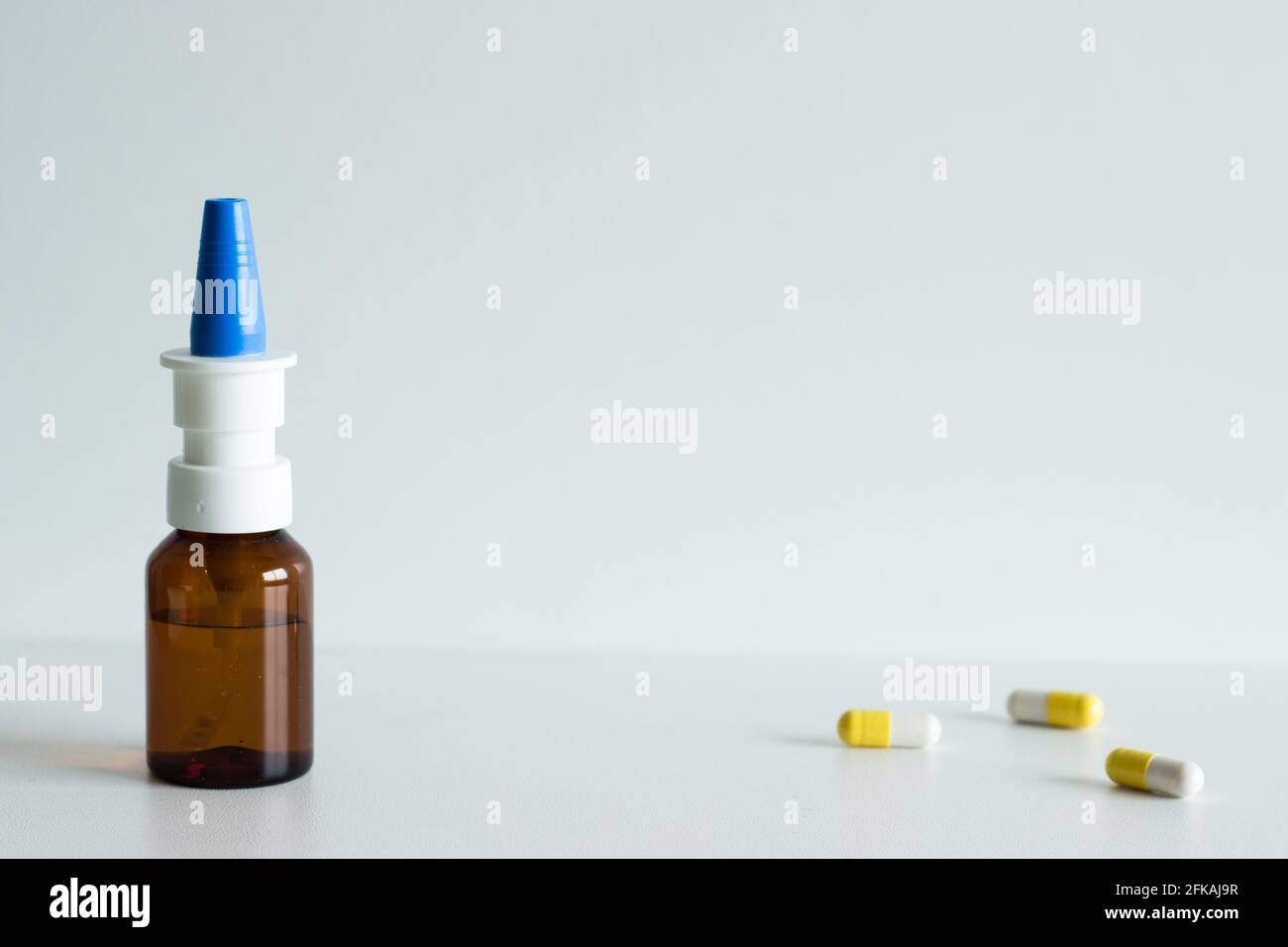 Nasal spray and yellow and white pills on the side Stock Photo