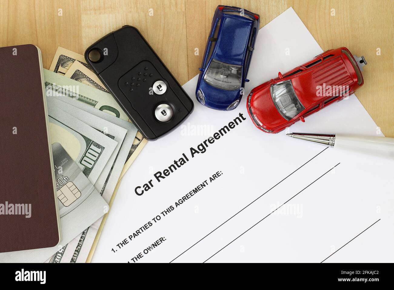 Car rental agreement next to car key, passport, cash and credit card