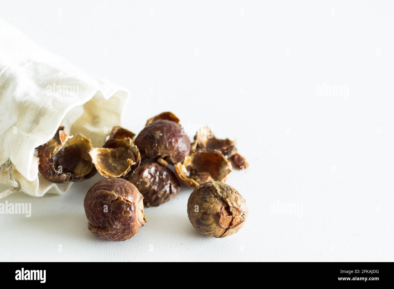 Soap nuts falling out of linen bag on white background; organic laundry detergent; eco-friendly Stock Photo