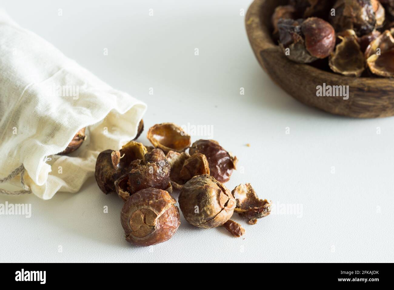Soap nuts falling out of linen bag on white background; organic laundry detergent; eco-friendly Stock Photo
