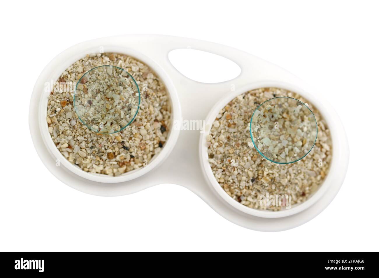 Contact Lens case full of sand and disposable lenses on top, conceptual idea for dry lenses and sand in the eyes Stock Photo
