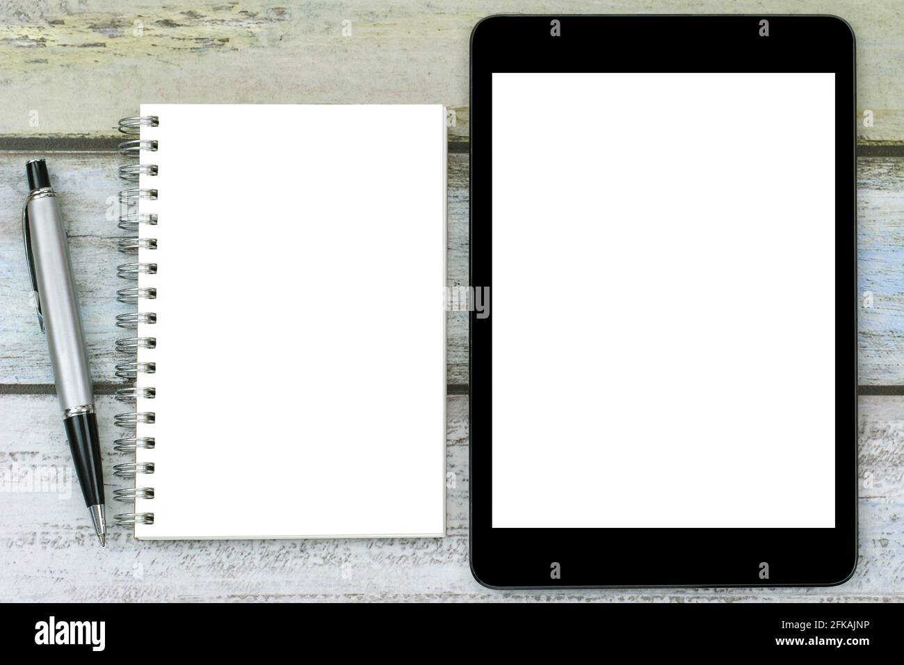 Blank notebook with a silver pen next to black tablet computer with white blank screen Stock Photo