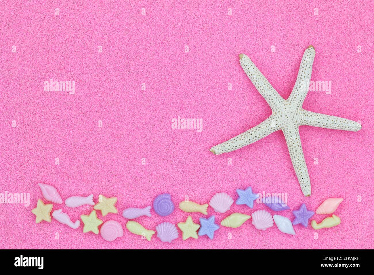 Closeup of star fish, known as sea stars, on pink fine sand beach background decorated with marine life beads Stock Photo