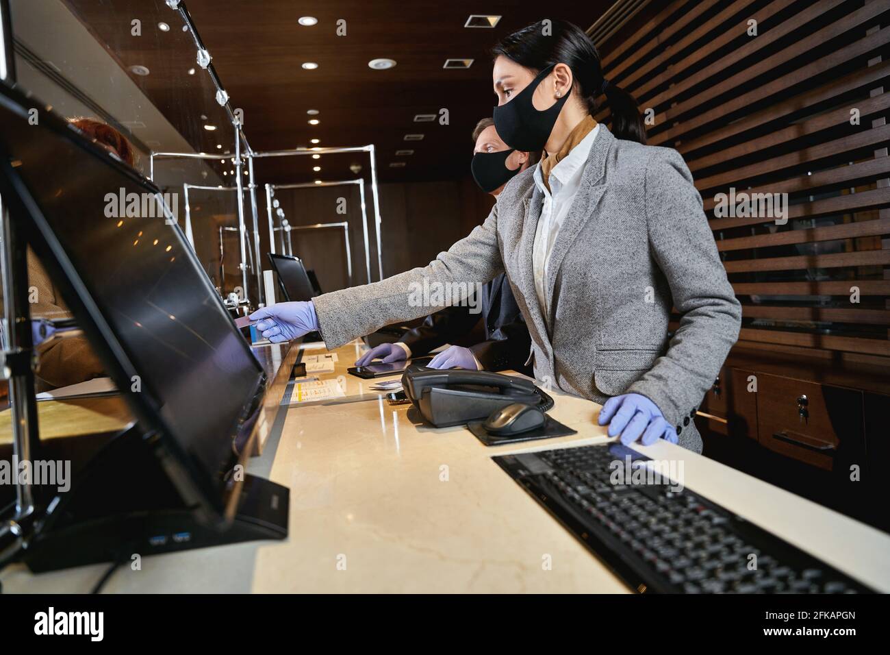 Hotel receptionists following the pandemic safety precautions Stock