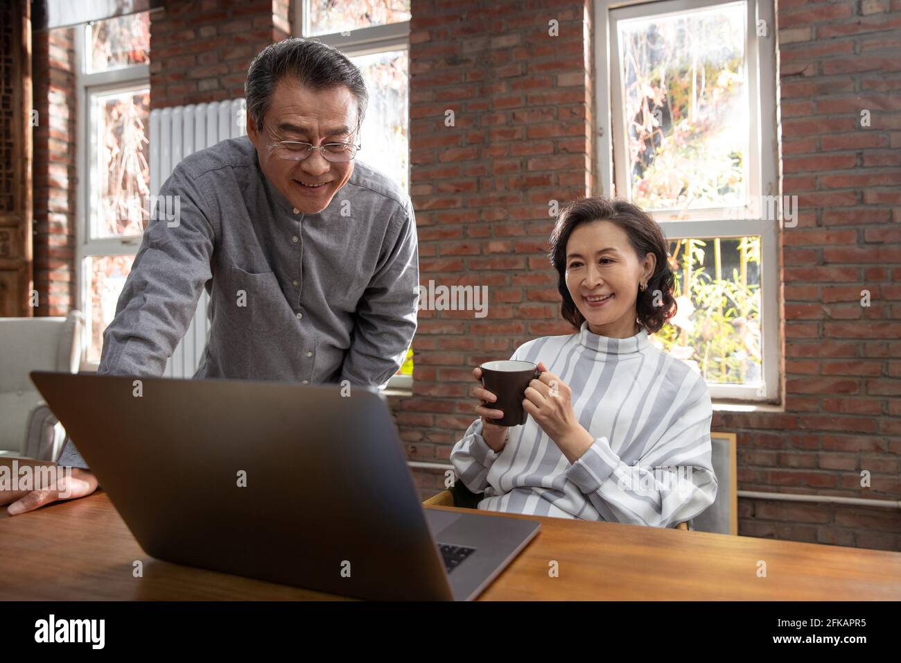 Happy elderly couple using laptops Stock Photo