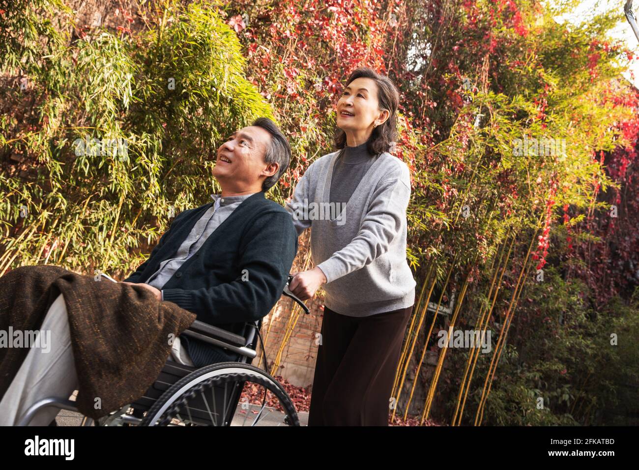 His wife of older women pushing a wheelchair Stock Photo