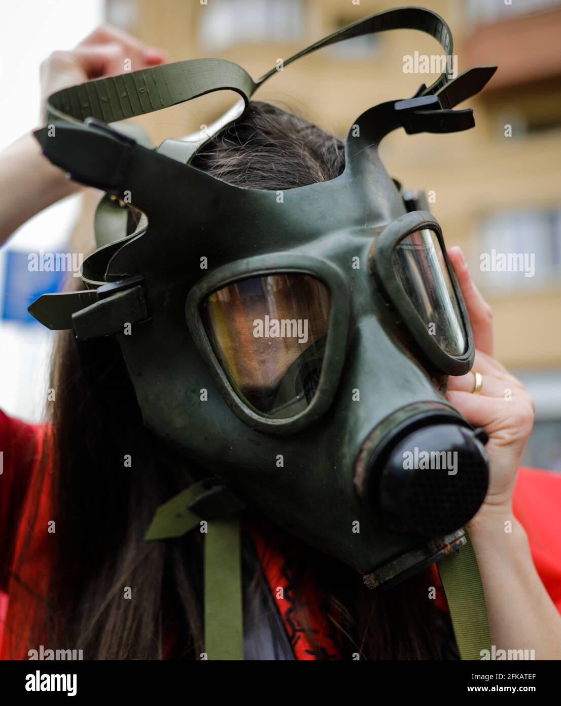 Shallow depth of field (selective focus) image with an old and worn out military gas mask without filters on the face of a woman. Stock Photo
