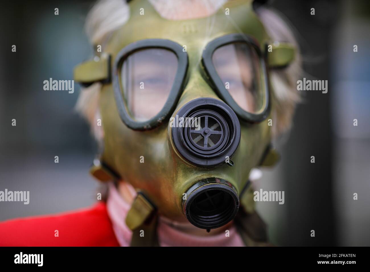 Shallow depth of field (selective focus) image with an old and worn out military gas mask without filters on the face of a senior woman. Stock Photo
