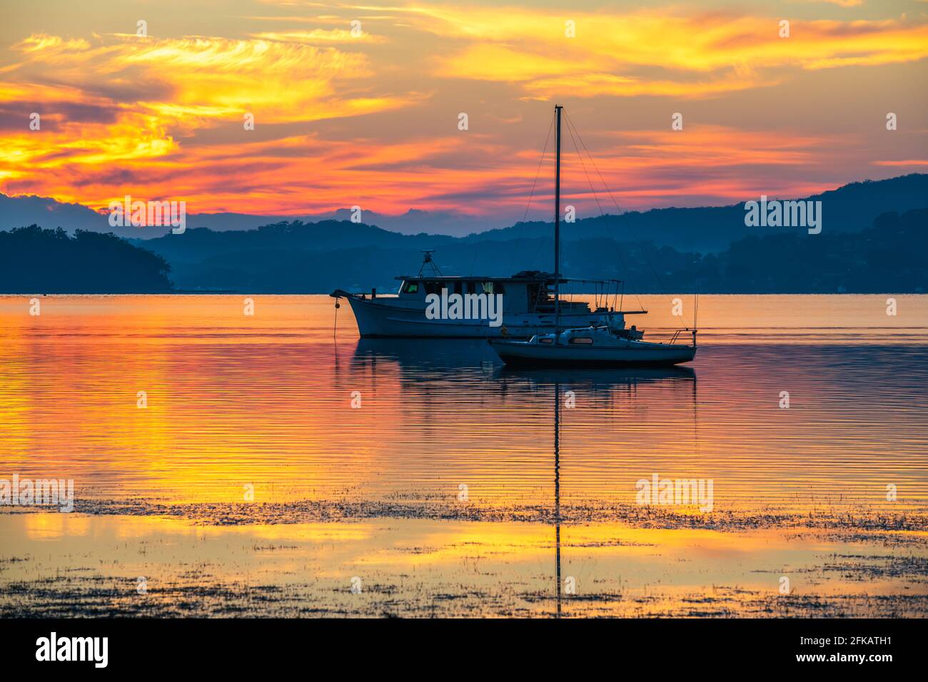 A pretty sunrise with boats and reflections at Koolewong Waterfront on the Central Coast, NSW, Australia. Stock Photo