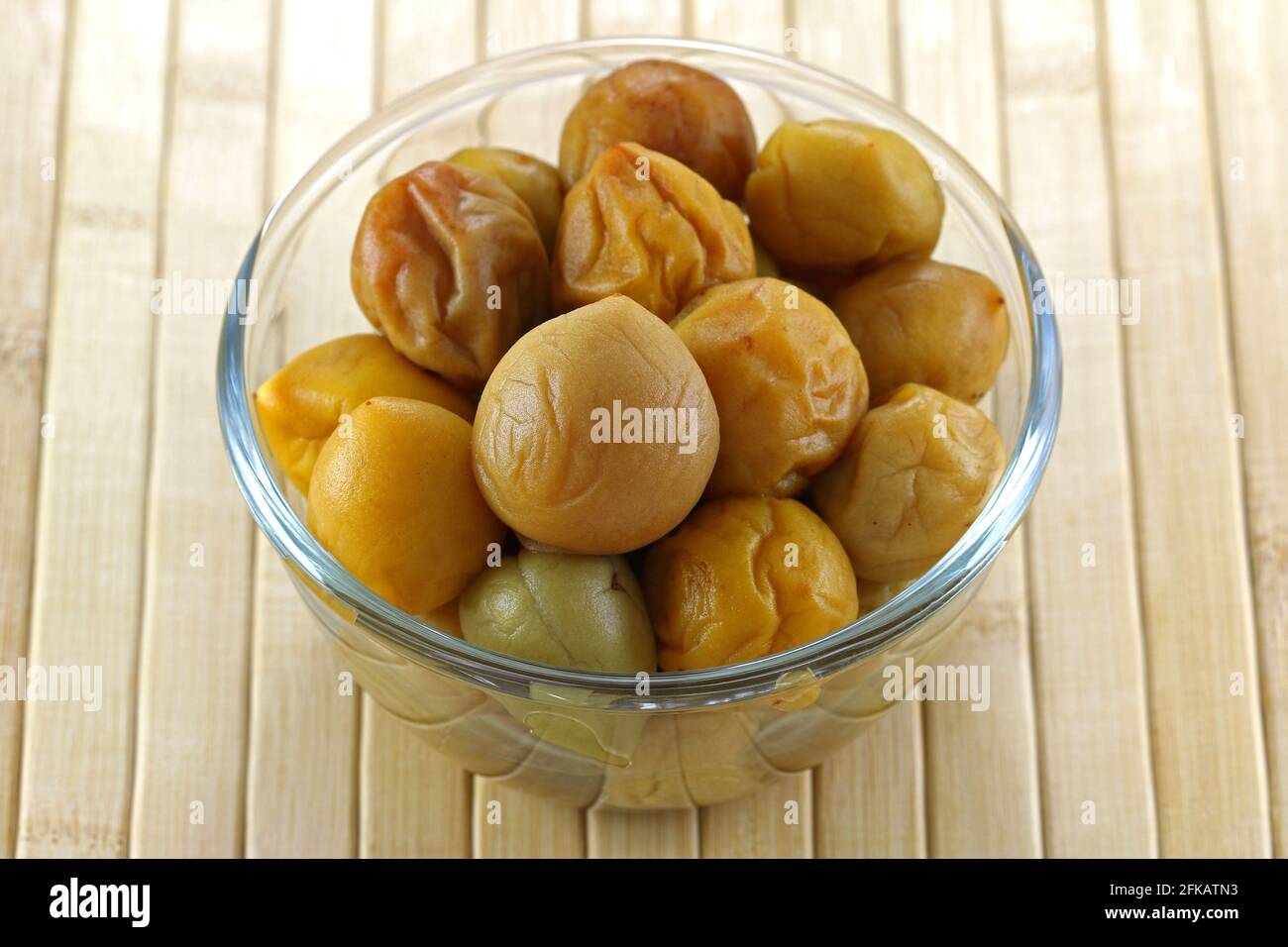 A bowl of pickled peach (Chinese plum, Japanese apricot), on a wooden mat Stock Photo