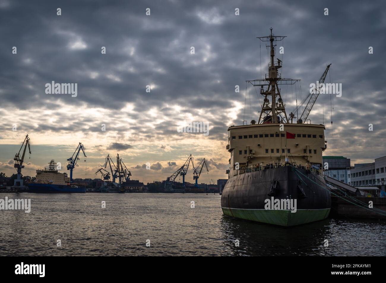 Lonely icebreaker ship surrounded by cranes at sunrise Stock Photo