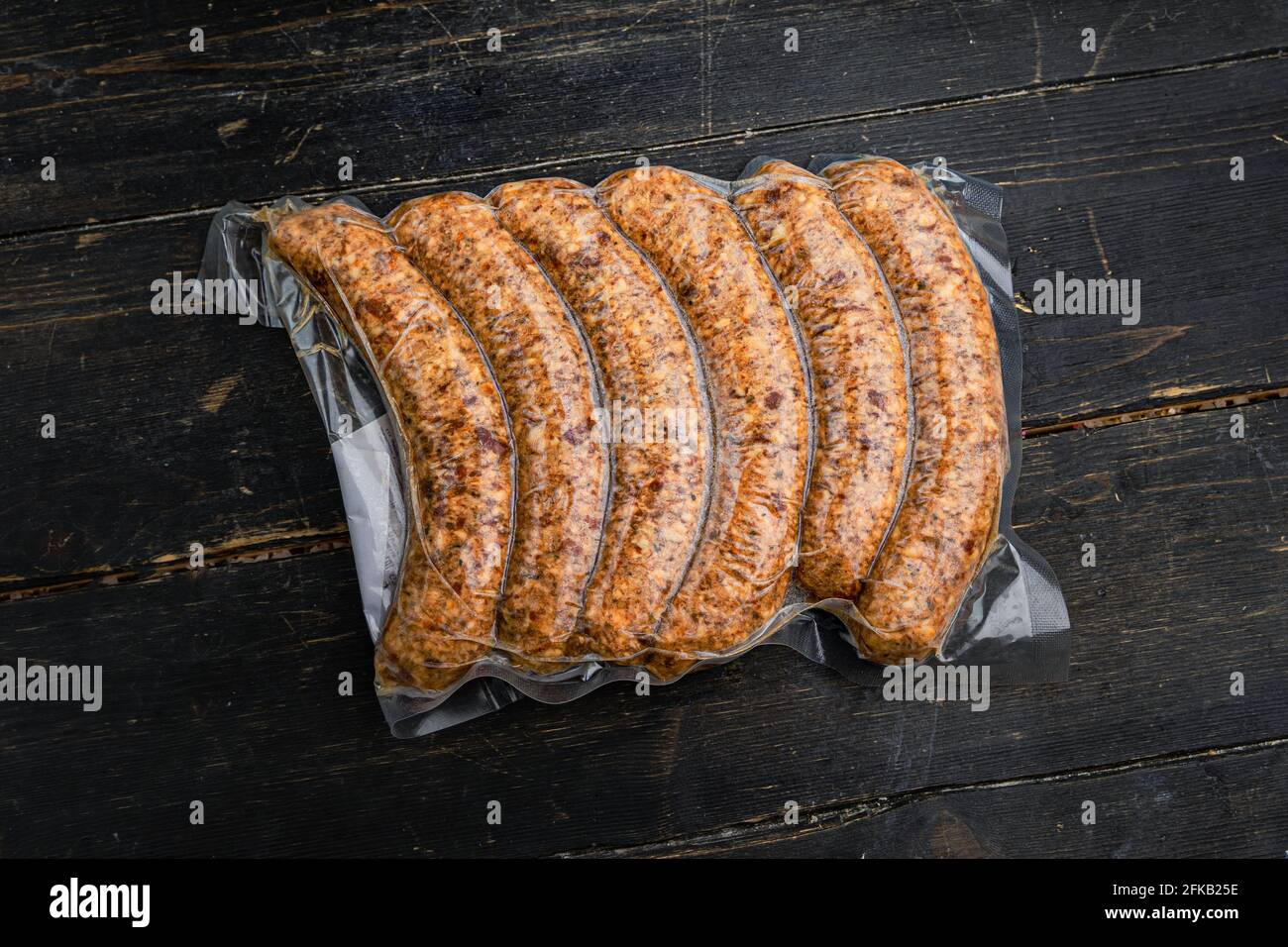 Vacuum-packed meat sausages or kupaty on a wooden background. Close up. Stock Photo