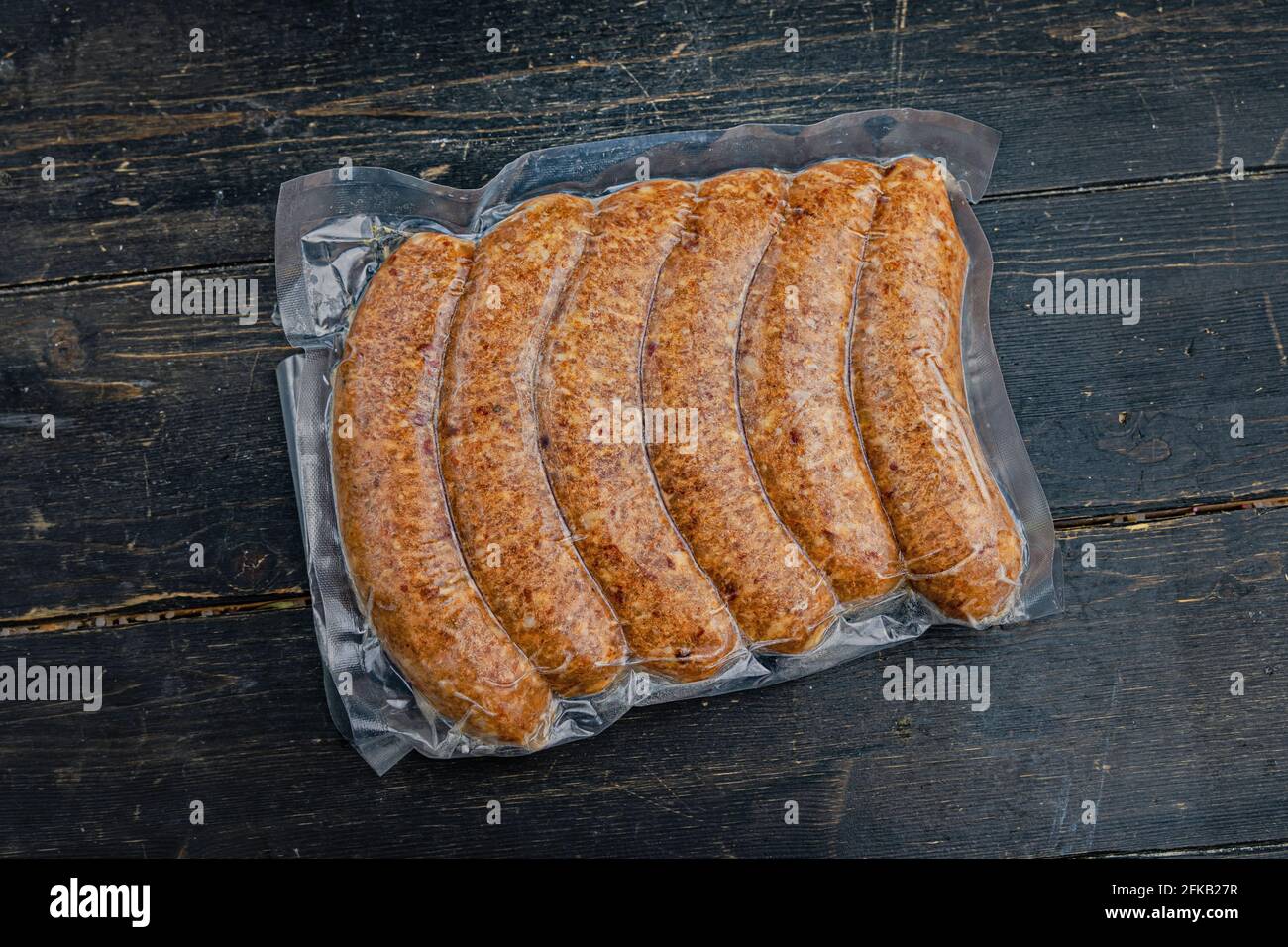 Vacuum-packed meat sausages or kupaty on a wooden background. Close up. Stock Photo