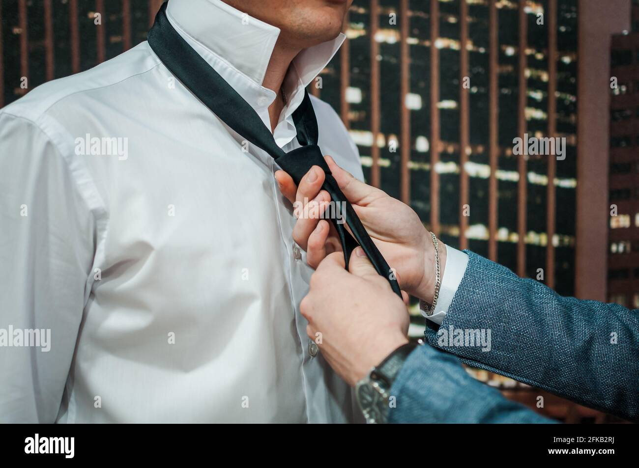 The man is tying a black tie. Groom's morning Stock Photo