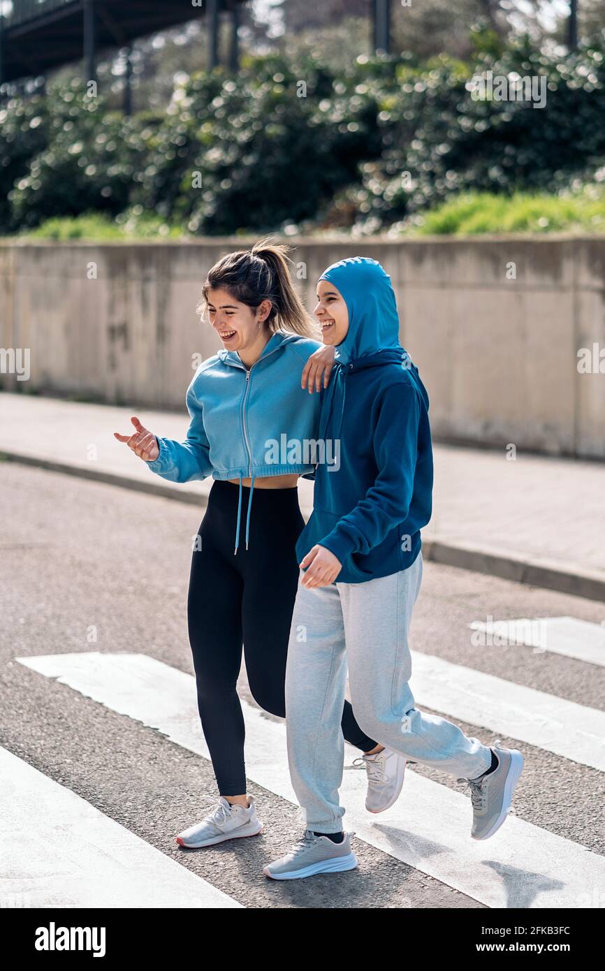 https://c8.alamy.com/comp/2FKB3FC/cheerful-active-girls-wearing-sports-clothes-walking-and-crossing-the-street-in-zebra-crossing-2FKB3FC.jpg