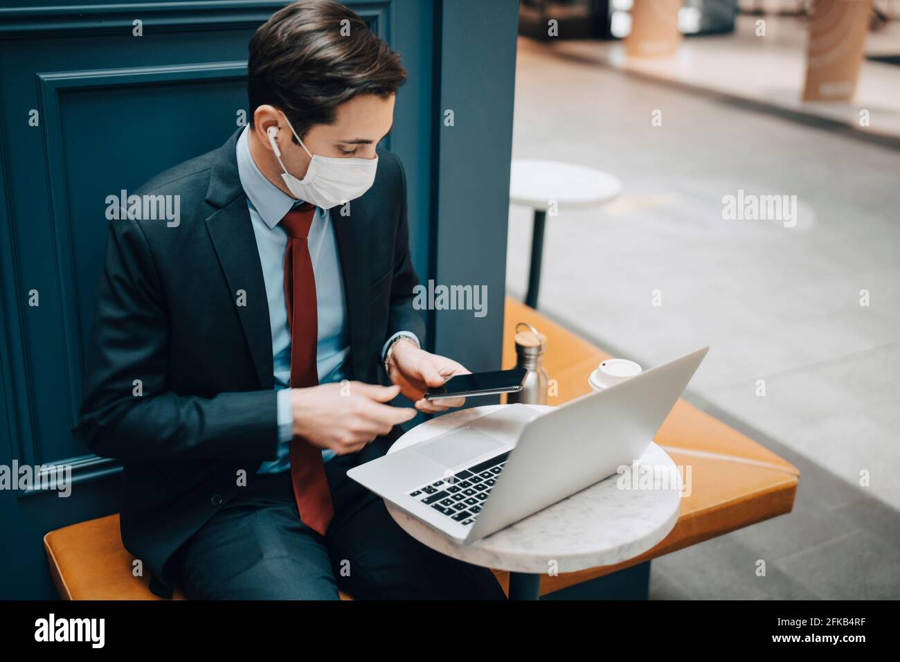 Businessman using smart phone with laptop in cafe Stock Photo
