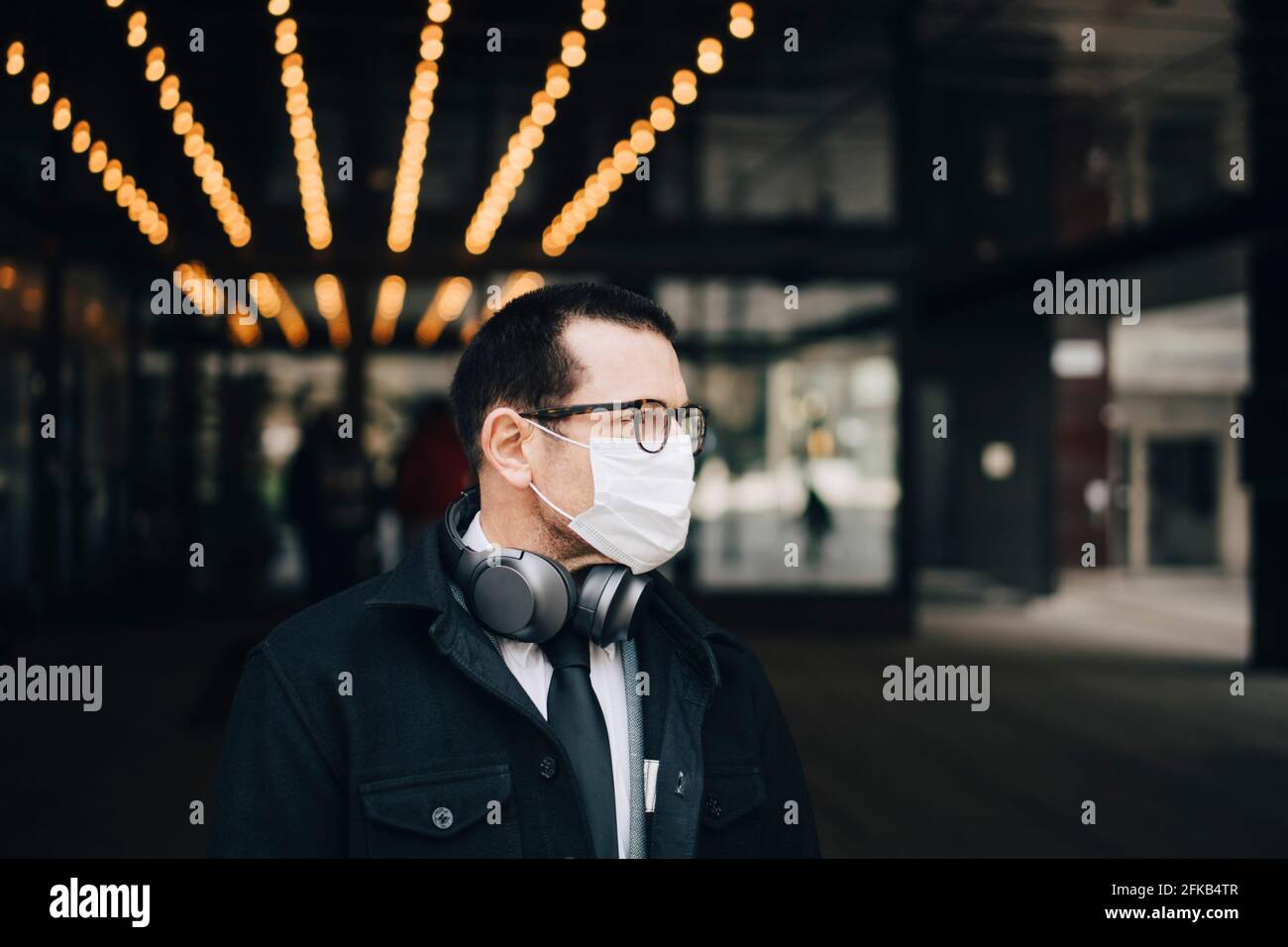 Businessman with headphones looking away during pandemic Stock Photo
