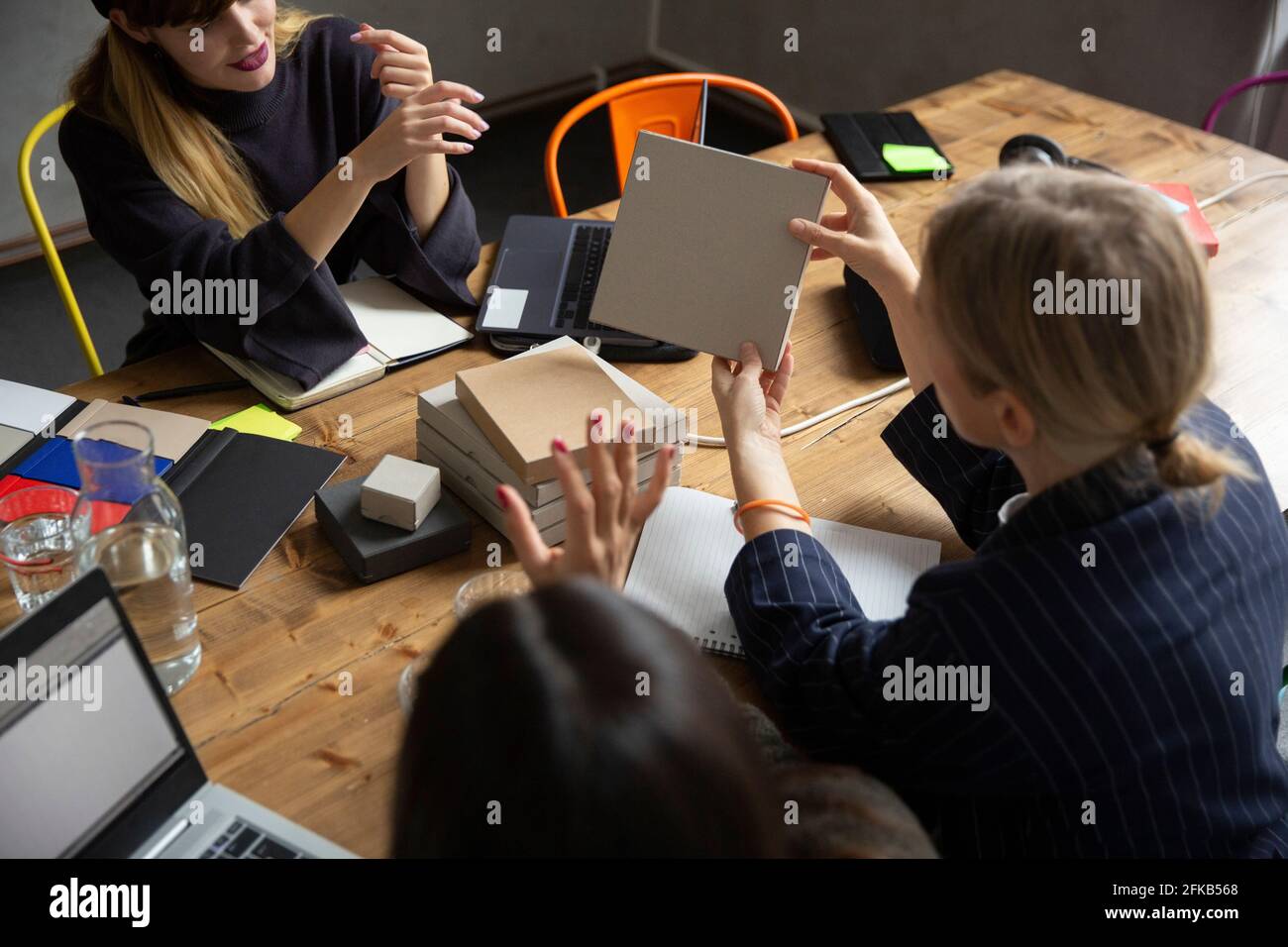 Businesswoman analyzing product with female colleagues at conference table in board room Stock Photo