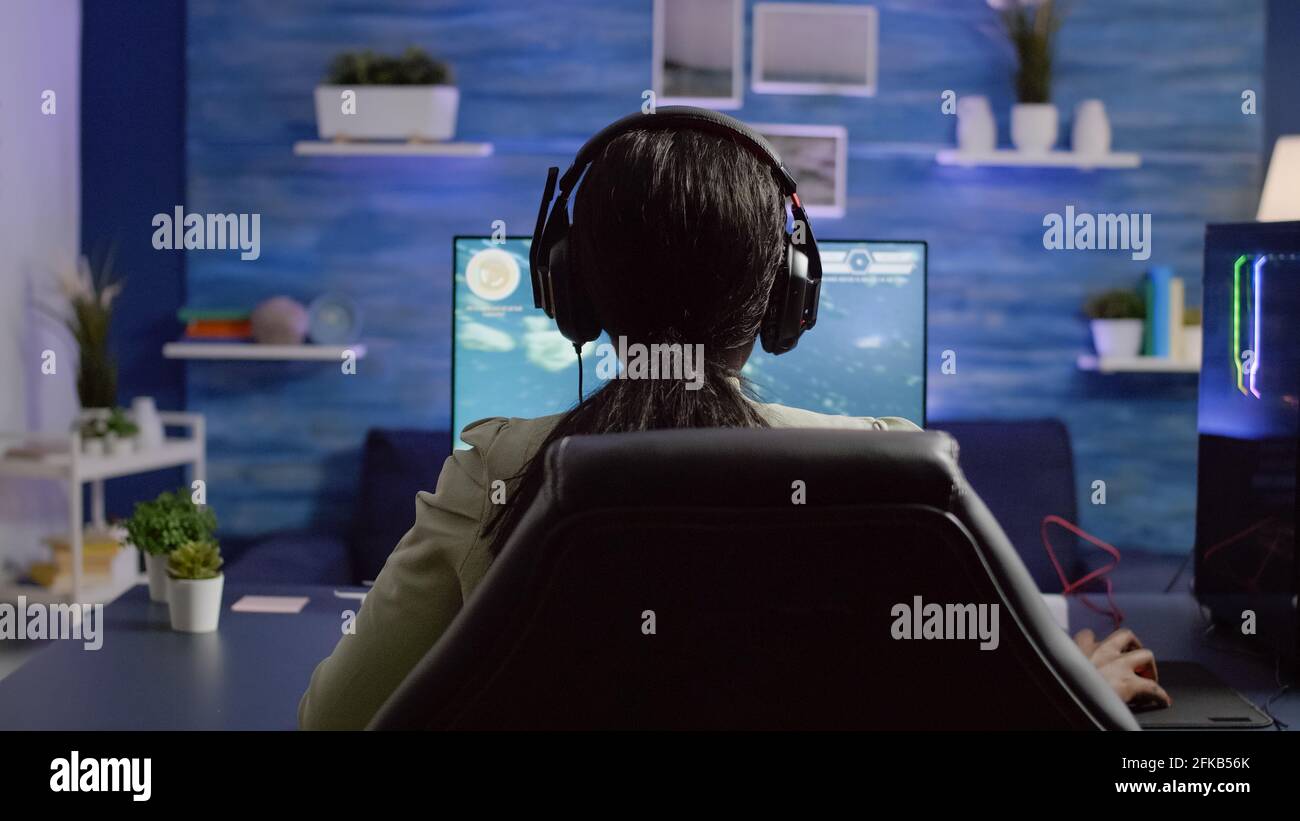 Back shot of streamer woman playing on RGB powerful computer shooter ...