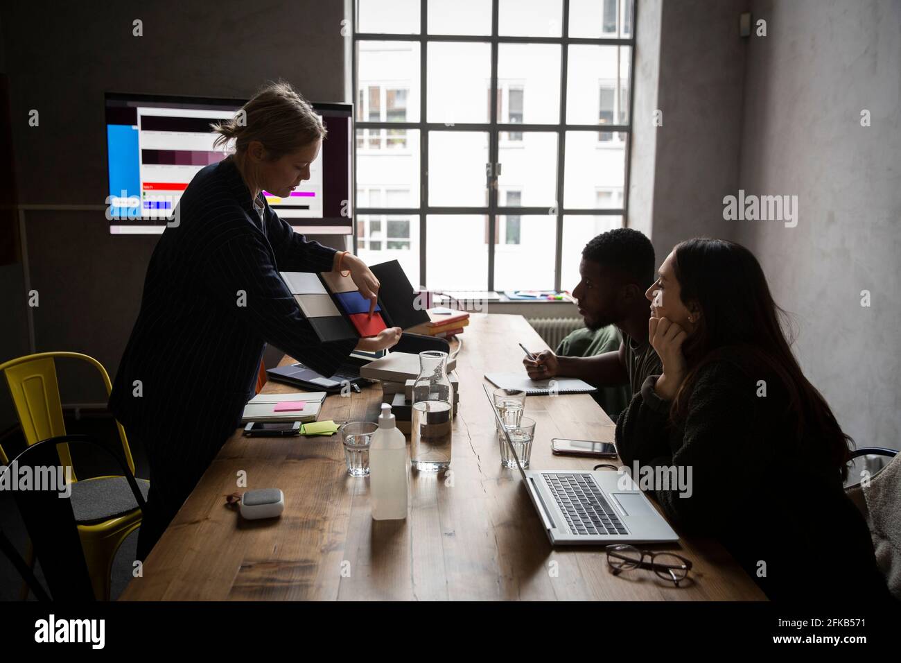 Businesswoman explaining about color swatch to colleagues at conference table in board room Stock Photo