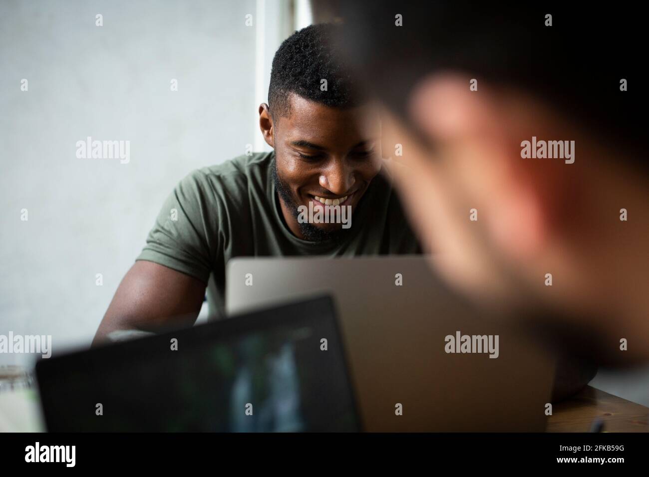 Smiling businessman working on laptop in office Stock Photo