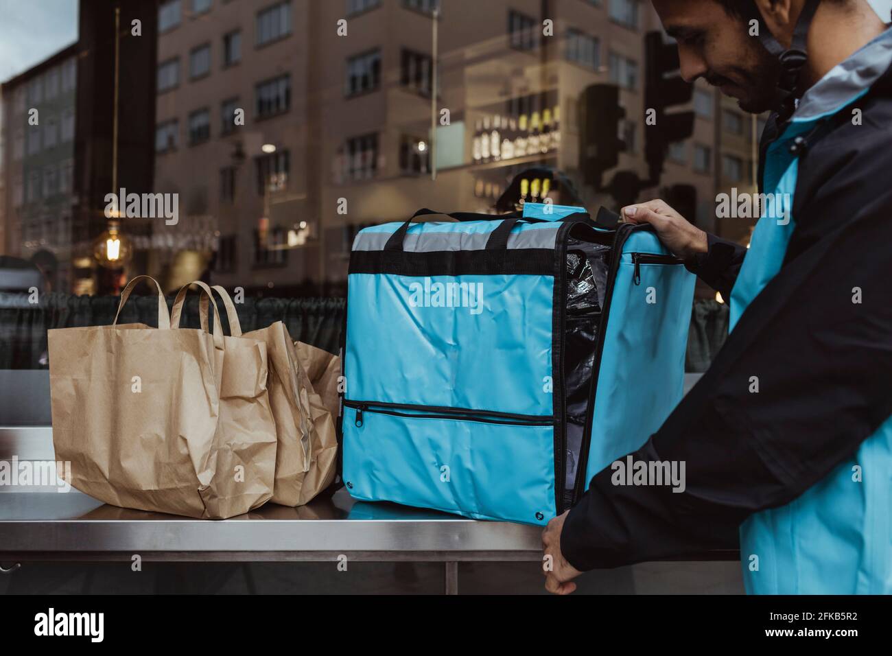 Deliver man standing by backpack outside deli store Stock Photo