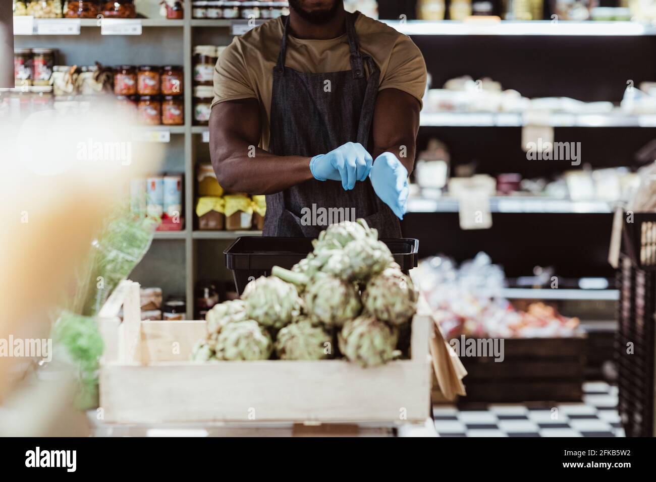 Midsection of male owner wearing gloves in deli store Stock Photo