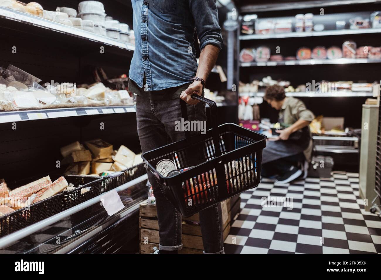 Midsection of male customer holding shopping basket at delicatessen shop Stock Photo